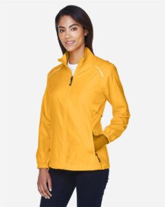 CORE365 78183 Women’s Techno Lite Motivate Unlined Lightweight Jacket – Campus Gold (on model side)