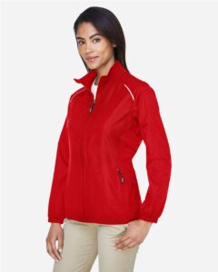 CORE365 78183 Women’s Techno Lite Motivate Unlined Lightweight Jacket – Classic Red (on model side)