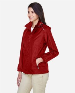 CORE365 78185 Women’s Climate Seam-Sealed Lightweight Variegated Ripstop Jacket – Classic Red (on model side)