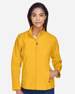 Team 365 TT80W Women’s Leader Soft Shell Jacket – Sport Athletic Gold (on model)